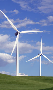 Wind turbines on a hill with blue sky.